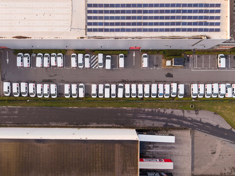 Vilvoorde, Belgium - 28 August 2026: Aerial view of the Cargovil industrial estate featuring a large warehouse roof covered with solar panels and rows of parked delivery vans.