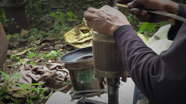 Mechanic Cleaning Electric Motor Shaft with Rag and Scraping Fitment Notch using Flat Metal Blade in Outdoor Workshop Environment for Water Pump Servicing