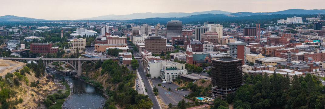 Spokane, United States - 15 August 2026: Aerial view of Spokane, featuring the Spokane River, the Monroe Street Bridge, and the urban skyline under an overcast sky.