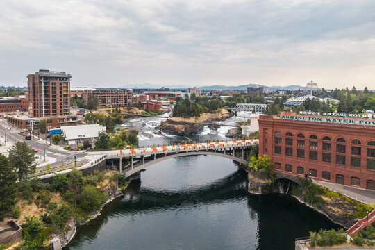 Spokane, United States - 15 August 2026: Aerial view of Spokane Falls, the historic Washington Water Power building, and Monroe Street Bridge with the river flowing.