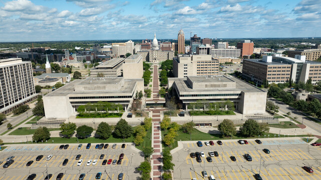 Lansing, Michigan, United States - 25 August 2026: Aerial view of the Michigan State Capitol and surrounding urban skyline with office buildings, parking lots, and trees.