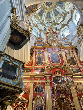 Ornate Baroque interior of a historic church in Kyiv, Ukraine, featuring a richly decorated red and gold iconostasis, religious paintings, gilded architectural details and an elaborate domed ceiling.