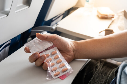 Passenger holding pills and medicines against cabin table during flight for her needs during long haul flight