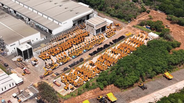 Aerial view of rows of yellow excavators and heavy construction machinery parked at a manufacturing unit in India.