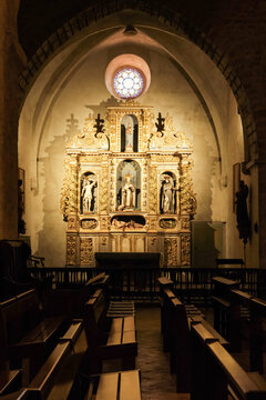 Interior view of the altarpiece (retable) inside Abbaye Sainte-Marie d'Arles-sur-Tech, featuring ornate golden baroque wood carvings, religious statues, and a stained glass rose window in France.