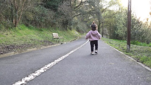 Toddler walking along outdoor park path in slow motion.