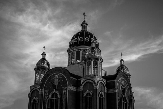 Ornate church beneath dramatic clouds in black and white
