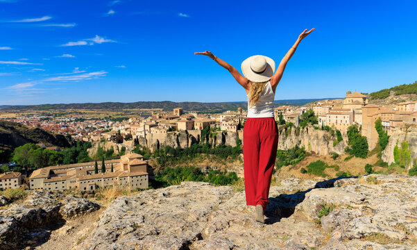 Happy woman tourist standing with raised arms enjoying panoramic view of Cuenca Spain