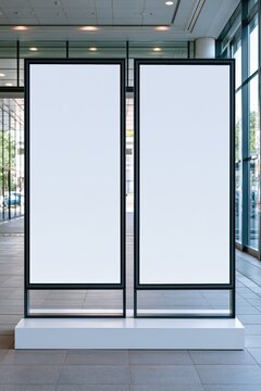 Two blank vertical digital advertising screens in a modern office building lobby, ready for content