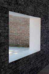 Una finestra su un muro di mattoni si affaccia su un cortile interno © Andrea Vismara