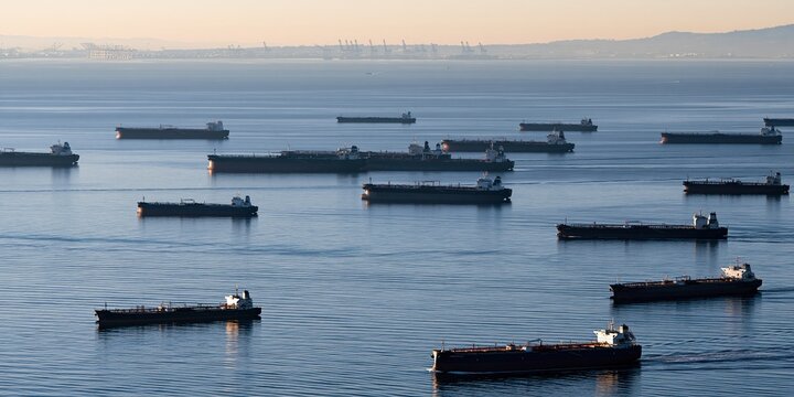 Large Fleet of Cargo Ships Anchored in the Ocean Under a Hazy Sky