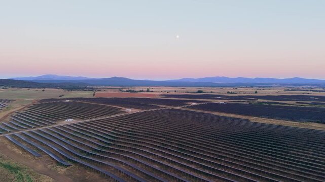 Aerial view of a large solar farm with rows of photovoltaic panels stretching across the rural landscape under a clear sky at sunset in Ciudad Rodrigo, Castile and Leon, Spain.
