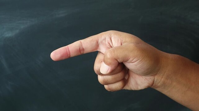 Close up of a human hand pointing with index finger against a dark background.