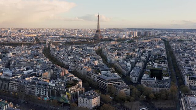 Aerial view of Eiffel Tower rising above the dense historic rooftops and urban streets of Paris, Ile-de-France, France.