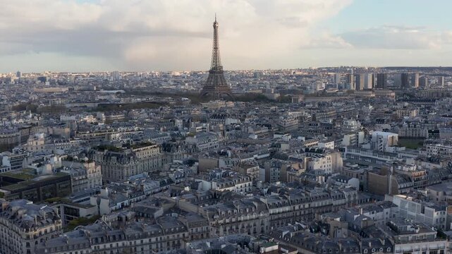 Aerial view of the iconic Eiffel Tower rising above the dense urban landscape of historic apartment buildings and streets in Paris, Ile-de-France, France.