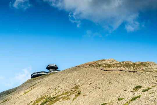 Karpacz, Poland - 28 July 2026: View of the iconic Snezka observatory building perched on the rocky summit of the mountain under a clear blue sky.