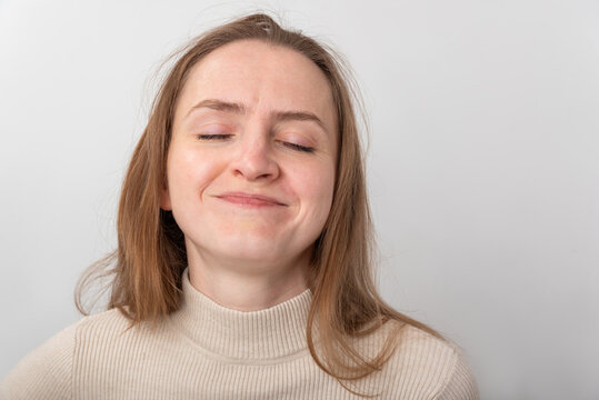 Young woman with eyes closed smiling peacefully, radiating calm happiness and contentment in a relaxed studio portrait conveying serenity, joy, and stress free ease
