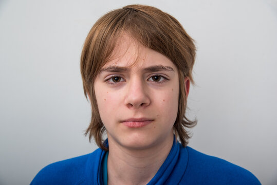 Young boy with brown hair and serious, direct gaze posing against a plain studio background, neutral headshot conveying childhood introspection, calm emotion and identity