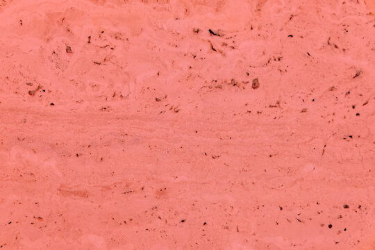 Pink marble surface presenting natural stone texture with horizontal striations and small porous details, creating a rough and organic background for various design applications