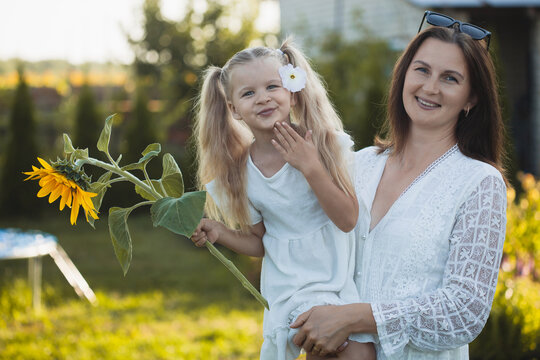 a cute five-year-old girl with mother in a white dress are playing in a green summer garden. happy childhood