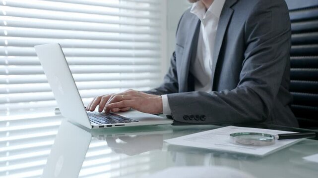 Business professional hands typing on a laptop keyboard during office work, creating a document, sending an email, or performing online research at his modern desk