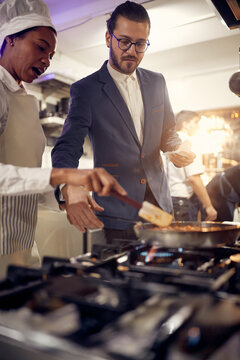 Cook in Professional Modern  kitchen, restaurant concept. chef explane about prepraring food to manager.