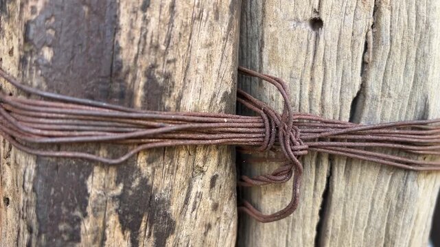 Rustic Ropes: Weathered wooden posts are tightly bound together by weathered wire, showcasing a rustic, aged texture and a sense of strong, enduring connection.