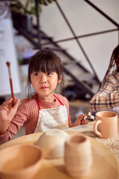 happy chinese girls painting with a brush at art class workshop. Creative, hobby ,activities concept