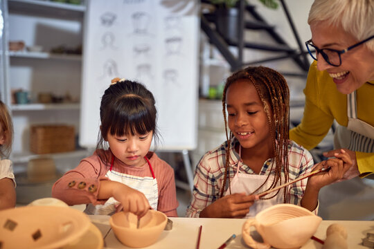  happy Creative kids painting handmade pot on a art class in school . Creative, hobby ,workshop  concept