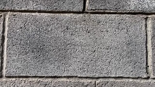 Close-up of weathered stone wall texture, showing rough grain and subtle imperfections, a study in tactile material