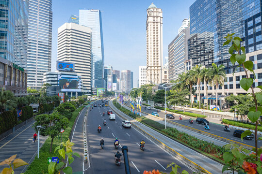 Jakarta, Indonesia - September 12, 2026: Traffic on Jenderal Sudirman Road surrounded by modern skyscrapers, office buildings, trees, and landscaped areas in central Jakarta.