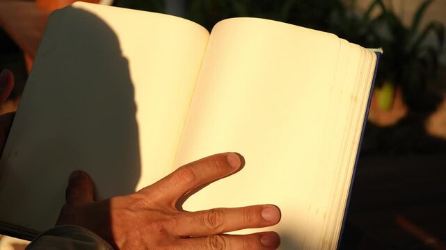 Close Up Hands Turning Blank Book Pages Under Warm Sunlight