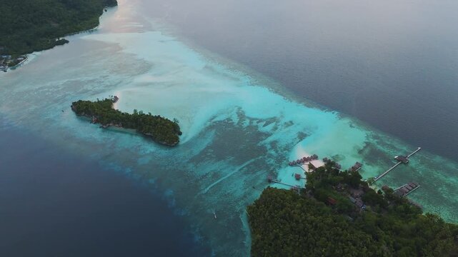 Aerial view of Raja Ampat Regency featuring Kri Island with turquoise waters, coral reefs, and overwater bungalows in Kri Island, Southwest Papua, Indonesia.