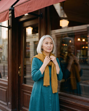 Curious mature woman walking past cafe storefront glancing upward with warm natural light