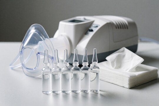 Medical nebulizer set with saline ampoules, transparent inhalation mask, white compressor. Pro equipment for asthma treatment, respiratory care. Tissues nearby for patient hygiene during nebulization