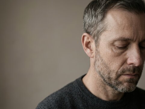 A contemplative middle-aged man with gray hair is pictured in soft light.