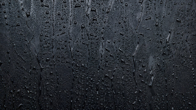 Dark slate background with water droplets, wet black stone texture, moody rain condensation on matte surface for product display