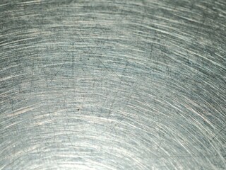 Fototapeta premium Scratches and circular swirl patterns on a worn stainless steel table top create an industrial metallic texture in a restaurant setting