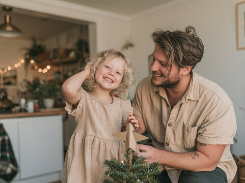 Father and daughter decorating the top of a Christmas tree at home