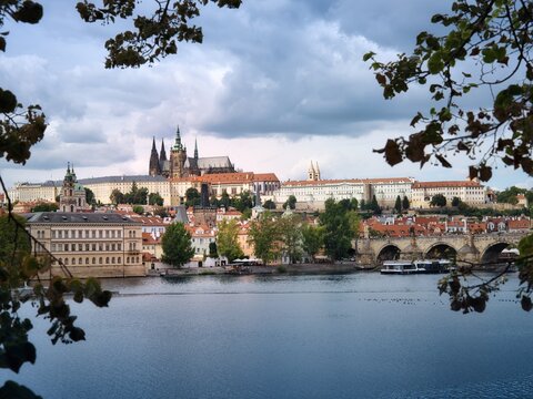 Scenic view of Prague Castle and St Vitus Cathedral above the Vltava River with historic Charles Bridge and Mal&aacute; Strana under dramatic clouds in Prague, Czech Republic.