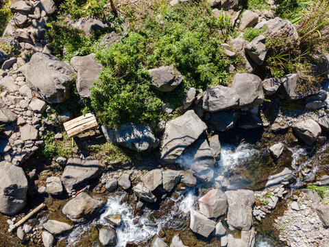 Aerial view of Rocky River with Pristine Waters Flowing Between Dense Forest Trees Covered with Moss and Vines in Indonesia. Serene Wilderness Landscape.