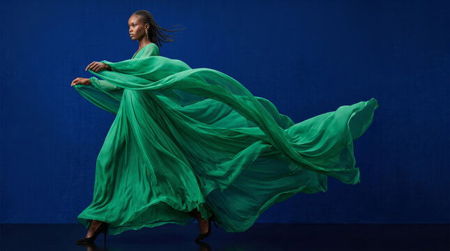 Fashion model in green silk gown with dynamic movement studio shot