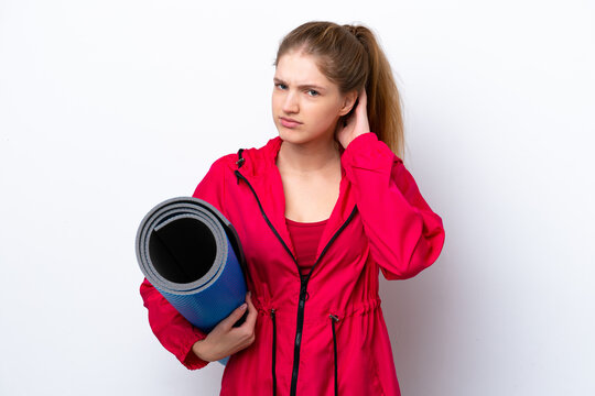 Teenager girl going to yoga classes while holding a mat isolated on white bakcground having doubts