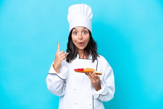 Young hispanic chef woman holding sashimi isolated on blue background intending to realizes the solution while lifting a finger up