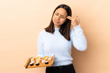 Young brunette mixed race woman holding sushi over isolated background with problems making suicide gesture © luismolinero