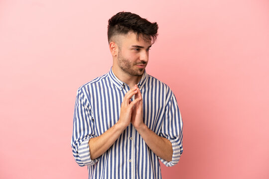 Young caucasian man isolated on pink background scheming something
