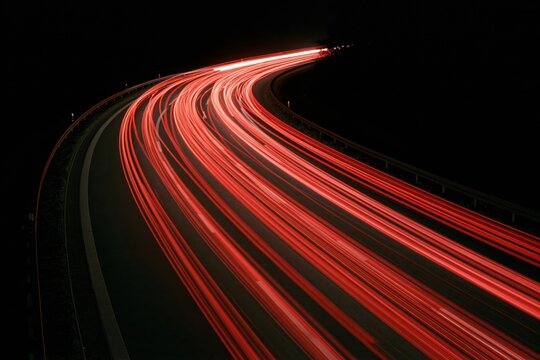 The Curving Highway Light Trails at Night: Red Streaks in Motion