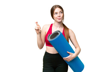 Young sport woman going to yoga classes while holding a mat over isolated chroma key background with fingers crossing and wishing the best © luismolinero