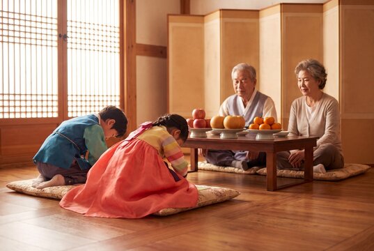 Children in traditional hanbok bowing to their grandparents on a holiday morning