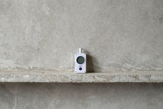 Portable radon detector measuring indoor air quality in unfinished concrete basement